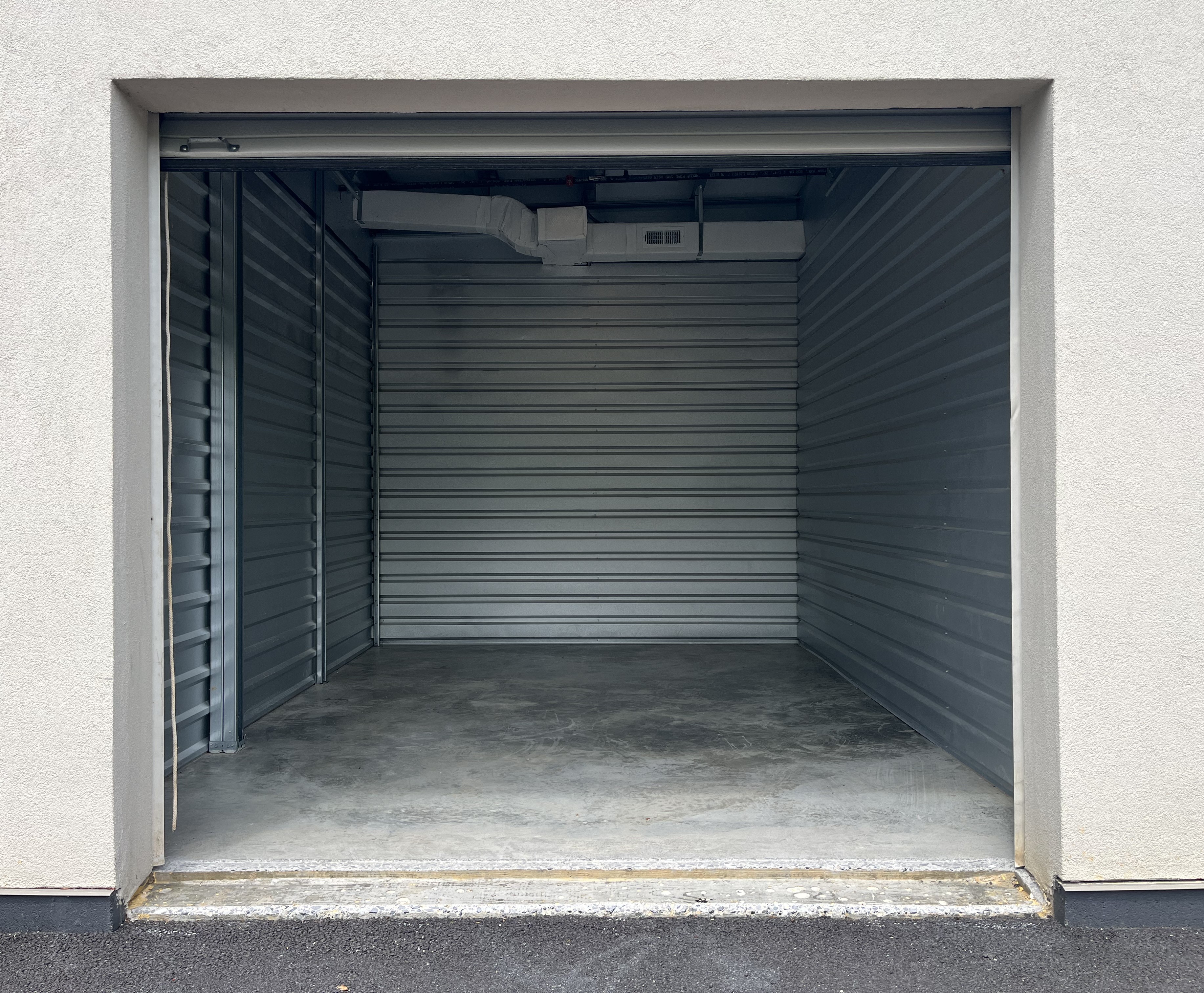An empty drive-up storage unit with a stucco exterior wall