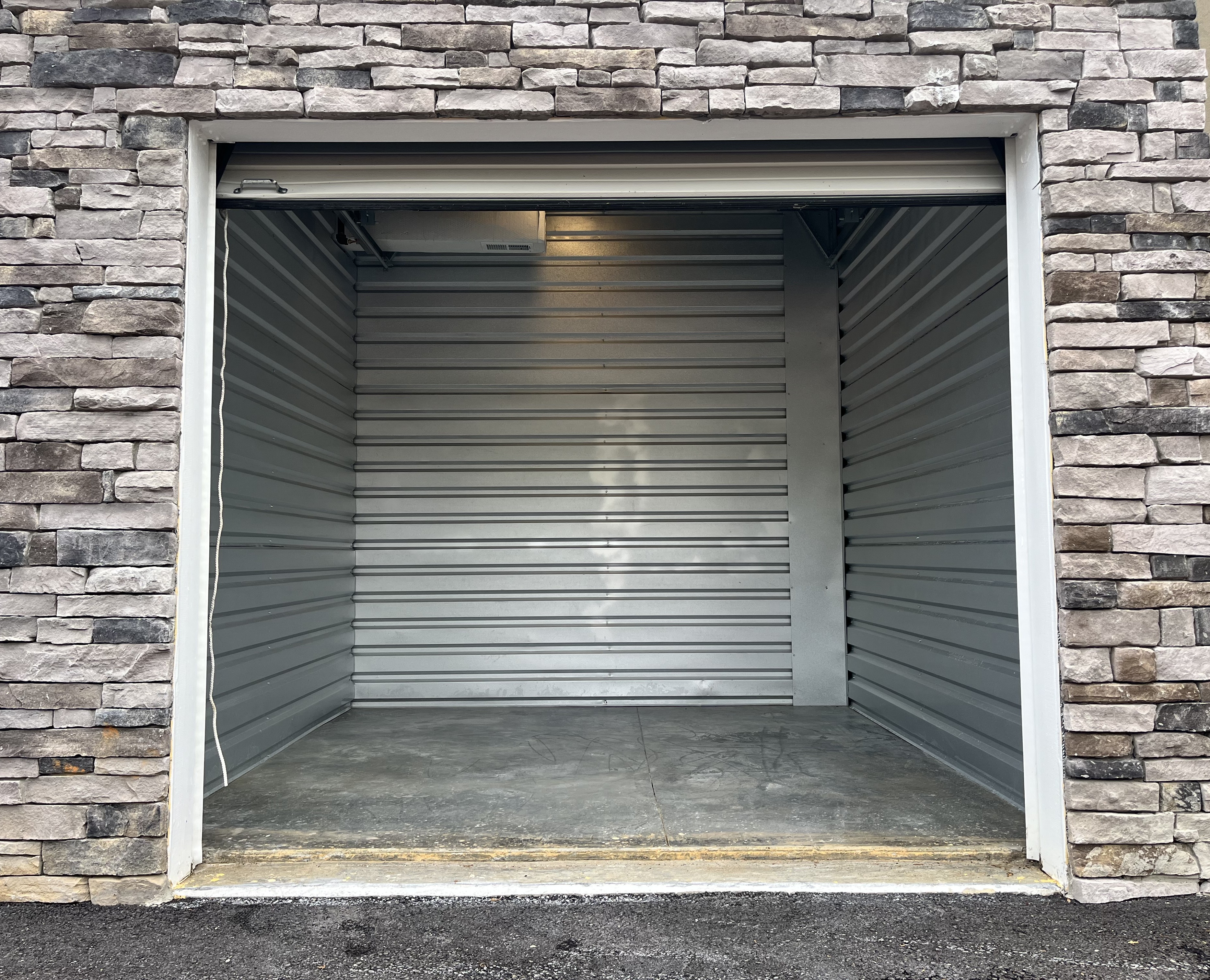 An empty drive-up storage unit with a stone exterior wall